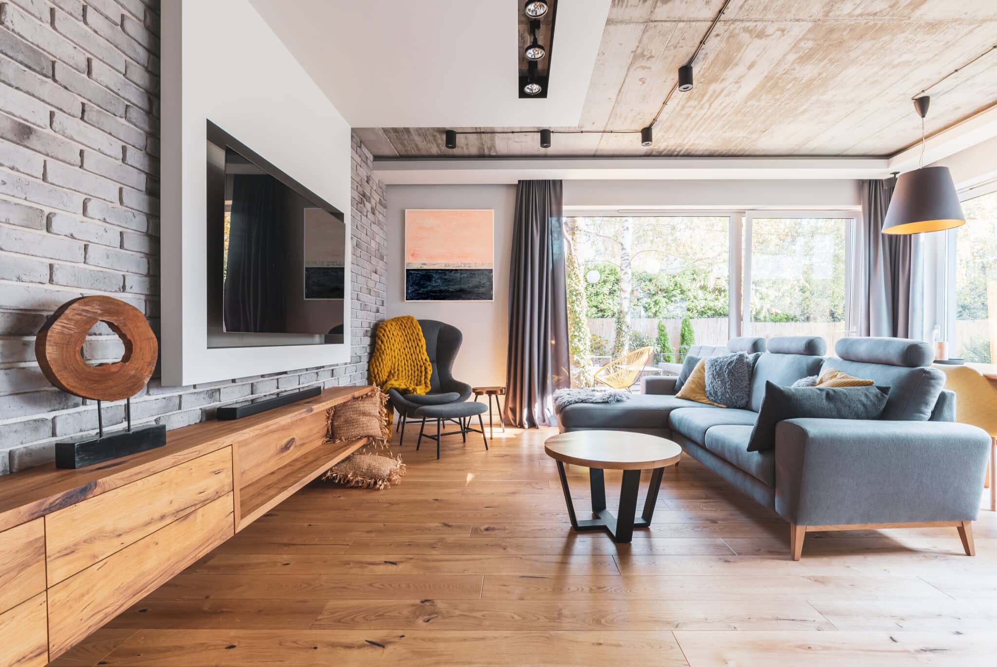 Elegant living room with light wood flooring, grey couch, and large picture window