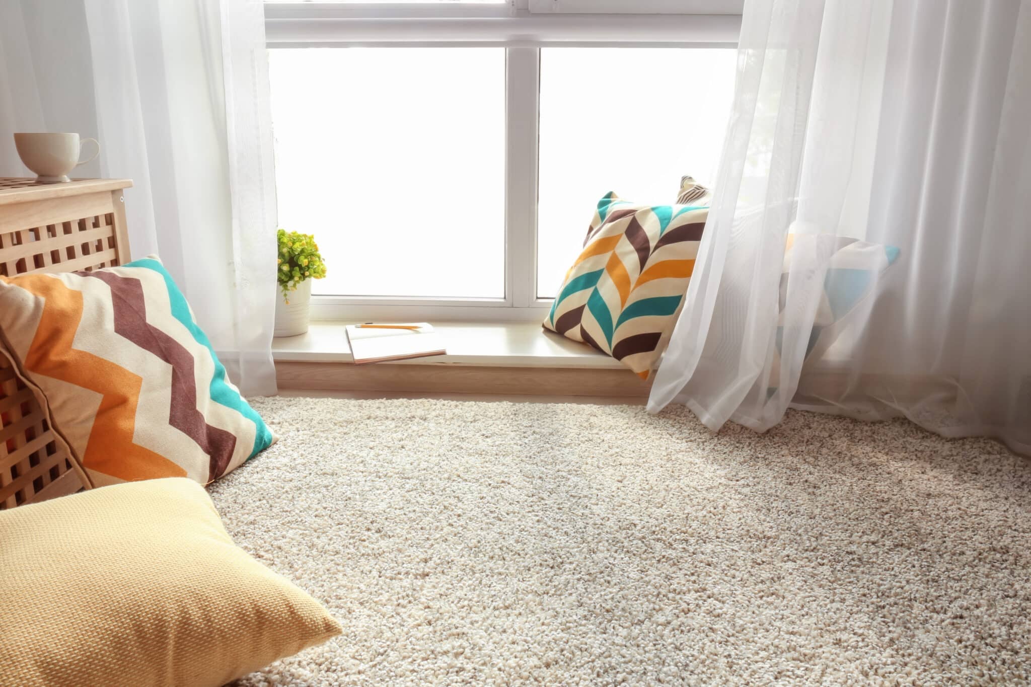 Cream carpet in a bright window nook with cushions and sheer curtains