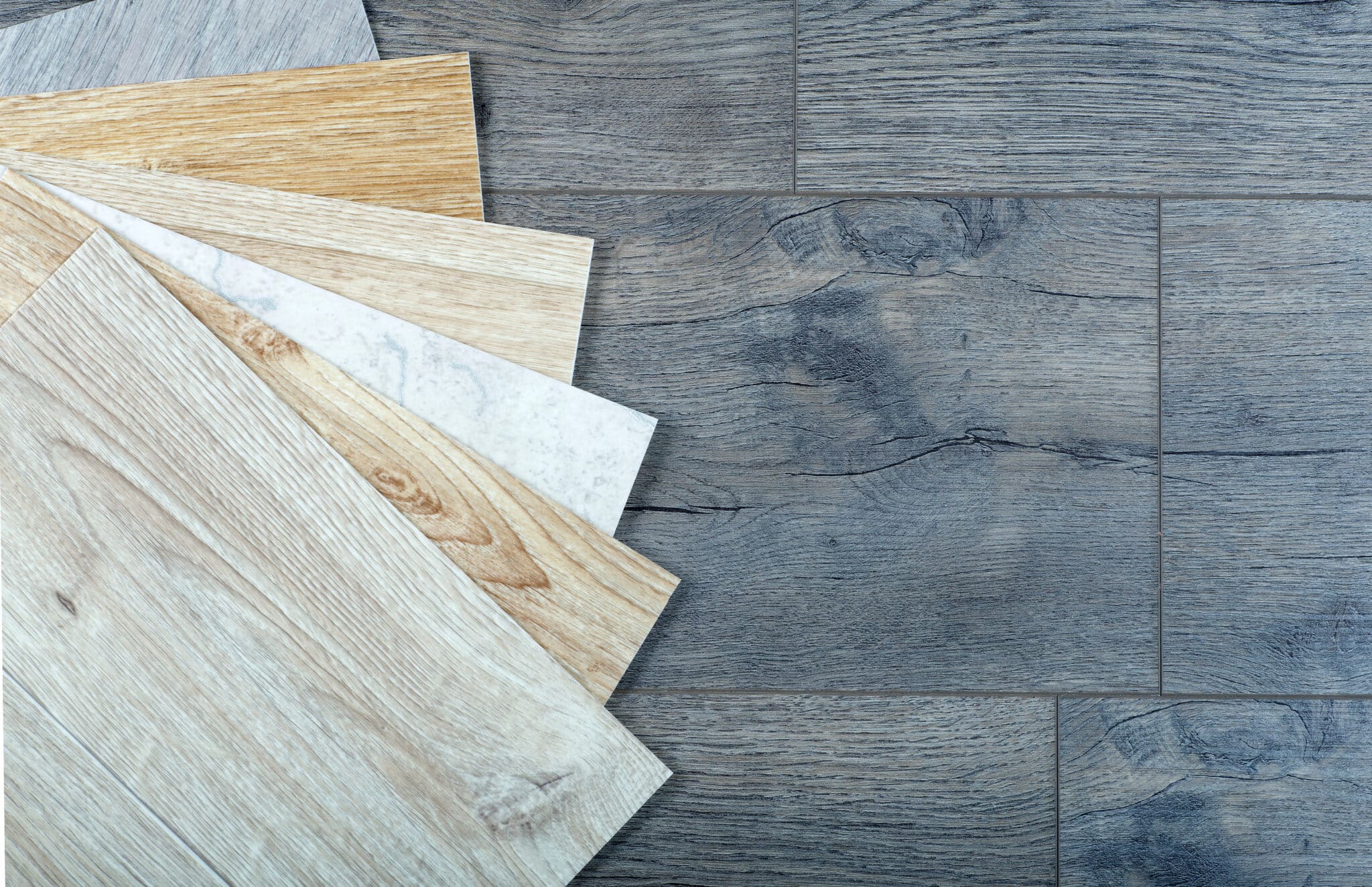 Fanned vinyl flooring samples in several colors laid out on a wooden surface