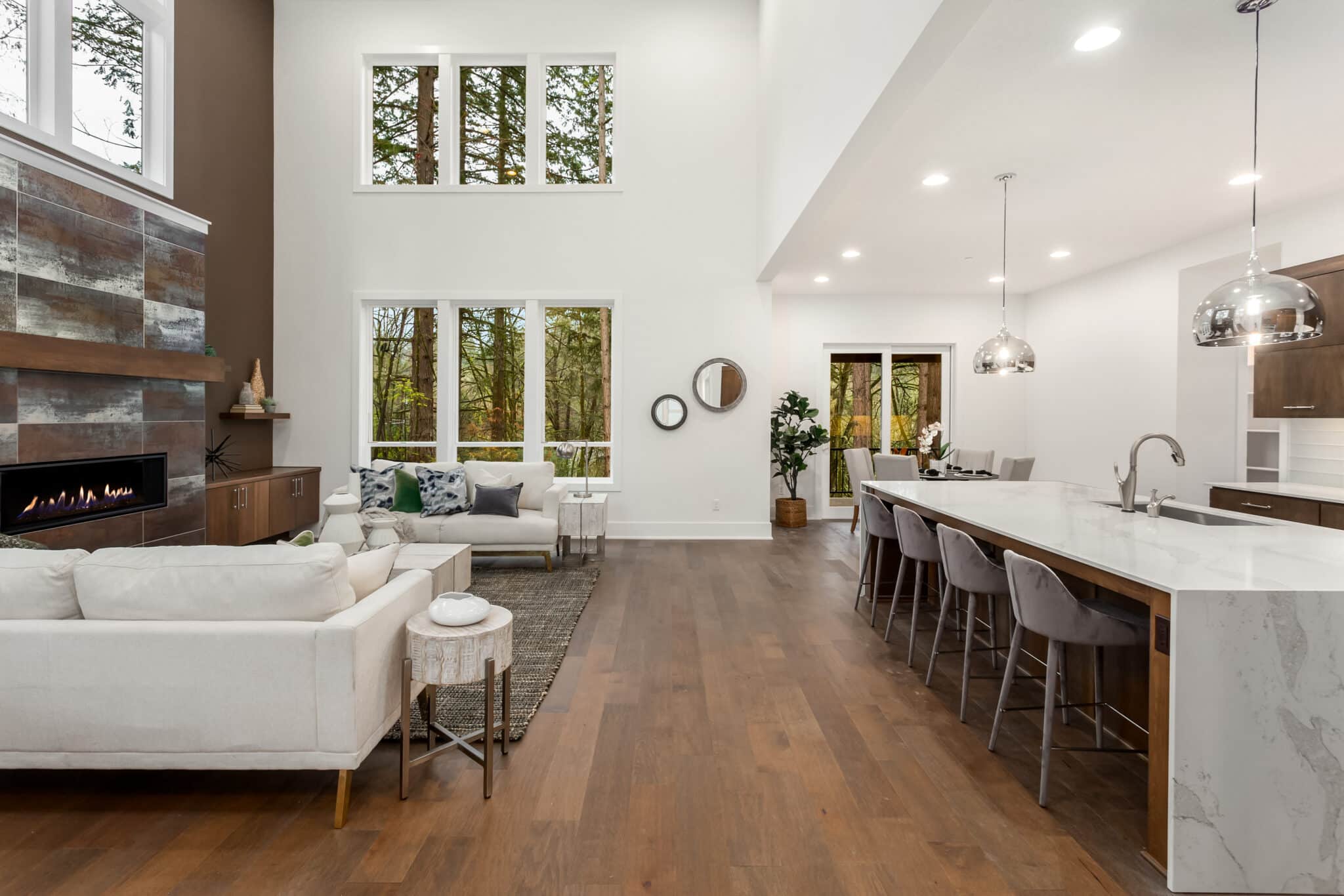 Open living room and kitchen with new hardwood flooring and large windows in a home